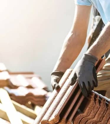 Artisan couvreur sur une toiture à muret